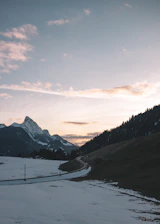 A serene sunrise over the snow-capped peaks of Spiti Valley, with winding roads below.