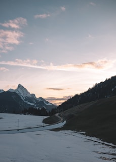 A serene mountain landscape during golden hour with a winding road.