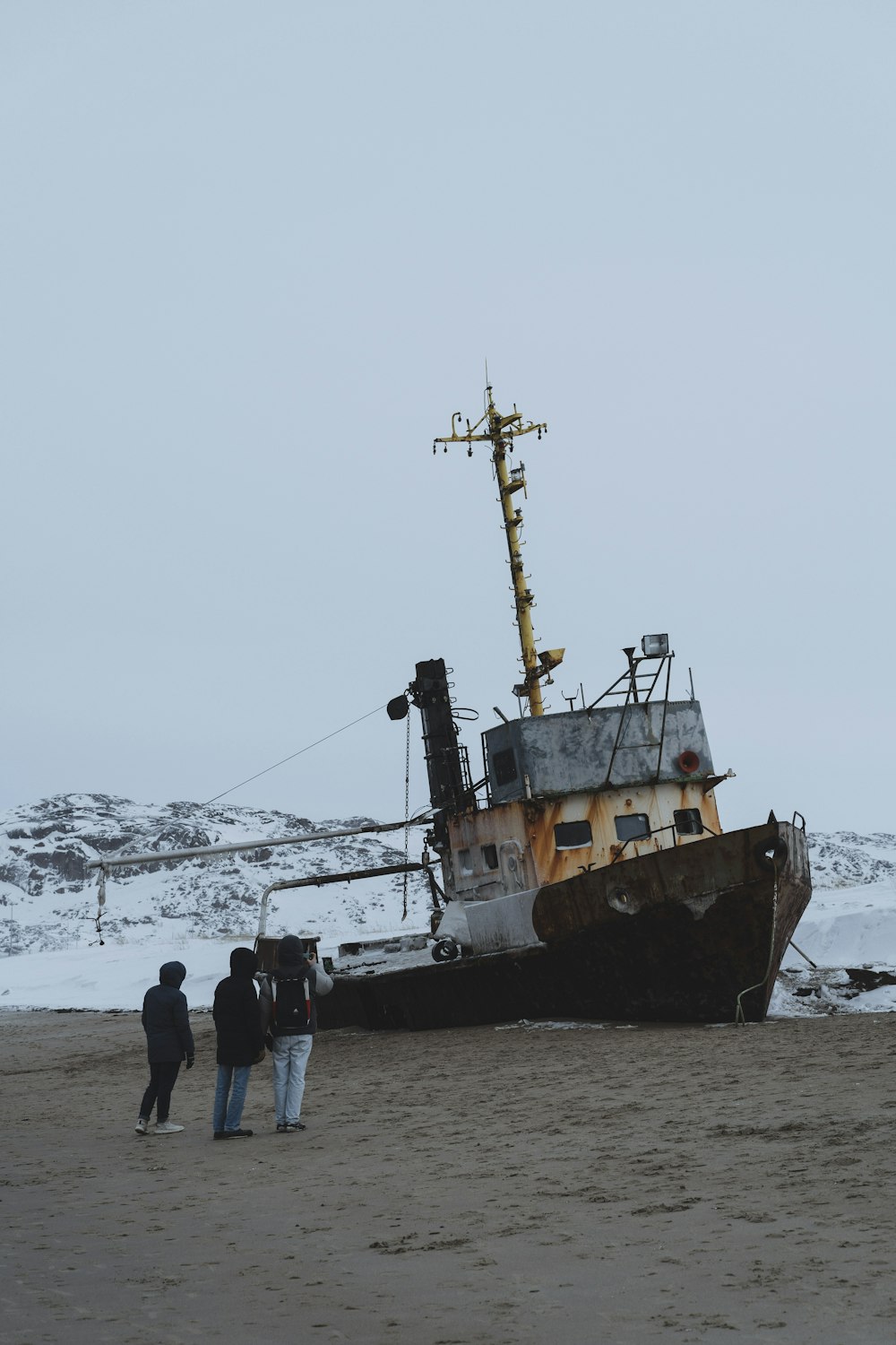 people standing on beach shore near brown ship during daytime