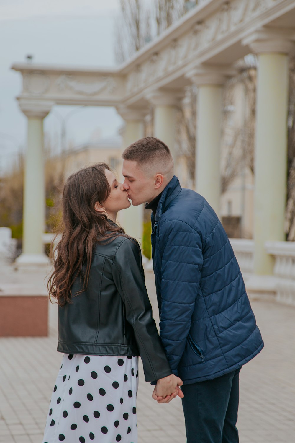 man in blue suit jacket kissing woman in black coat