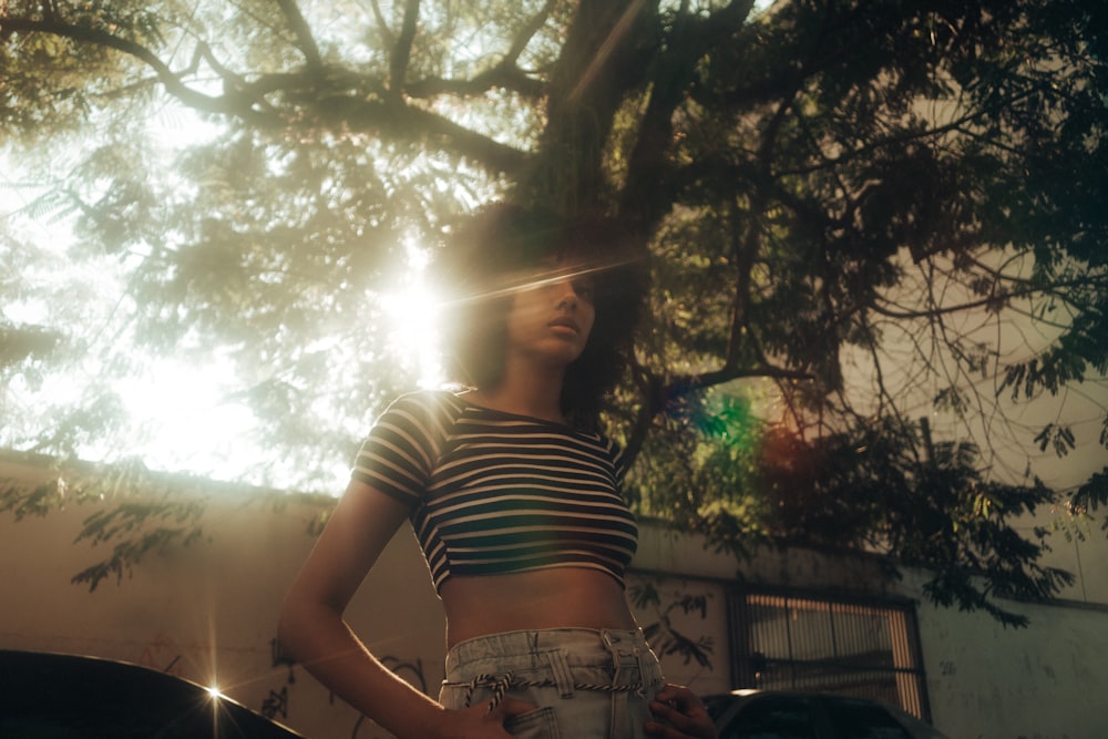 woman in black and white striped shirt standing near green tree during daytime