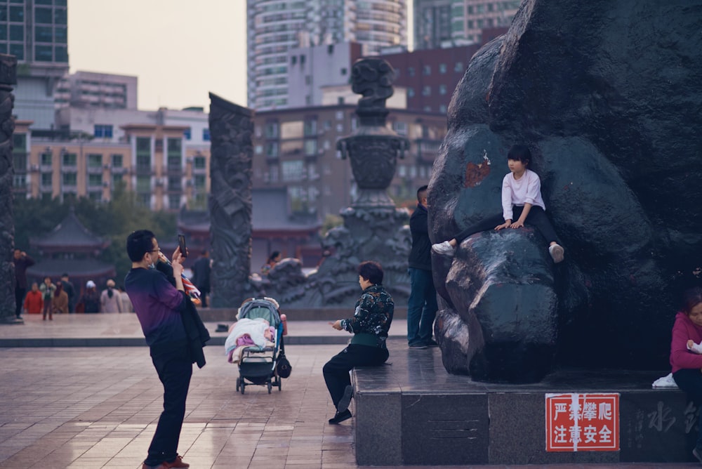 man in black jacket and black pants sitting on gray concrete bench during daytime