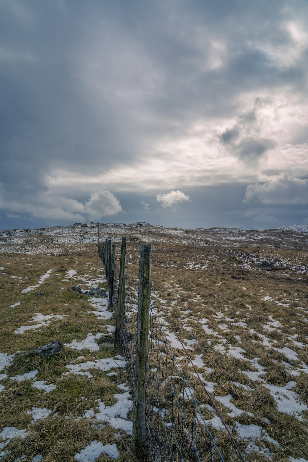 valla de madera marrón en arena marrón bajo nubes blancas durante el día