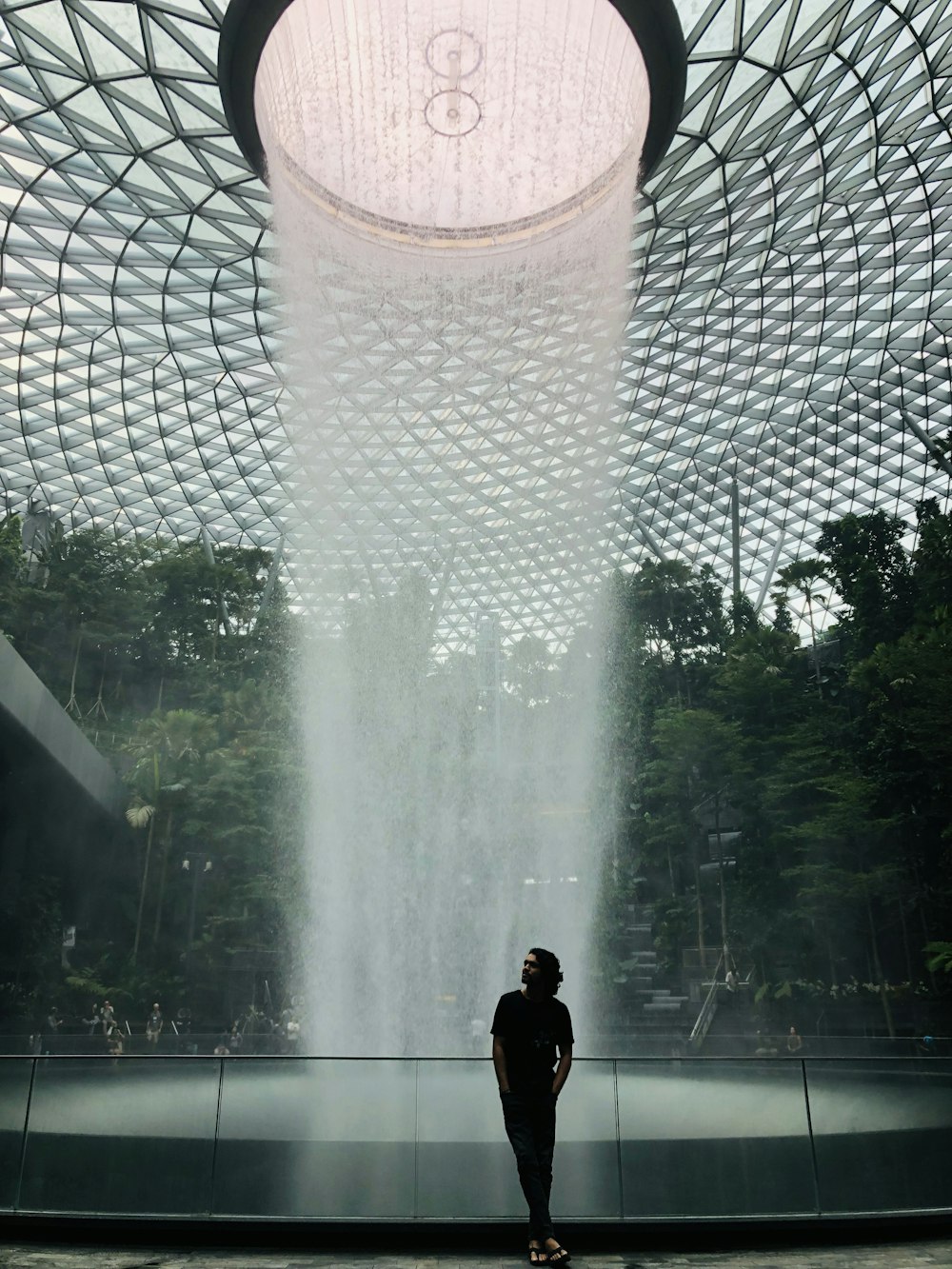 homme en t-shirt noir debout près de la fontaine d’eau