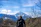 A man standing on a mountain trail, looking at the scenic view with a backpack.