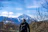 A man standing on a mountain trail, looking at the scenic view with a backpack.
