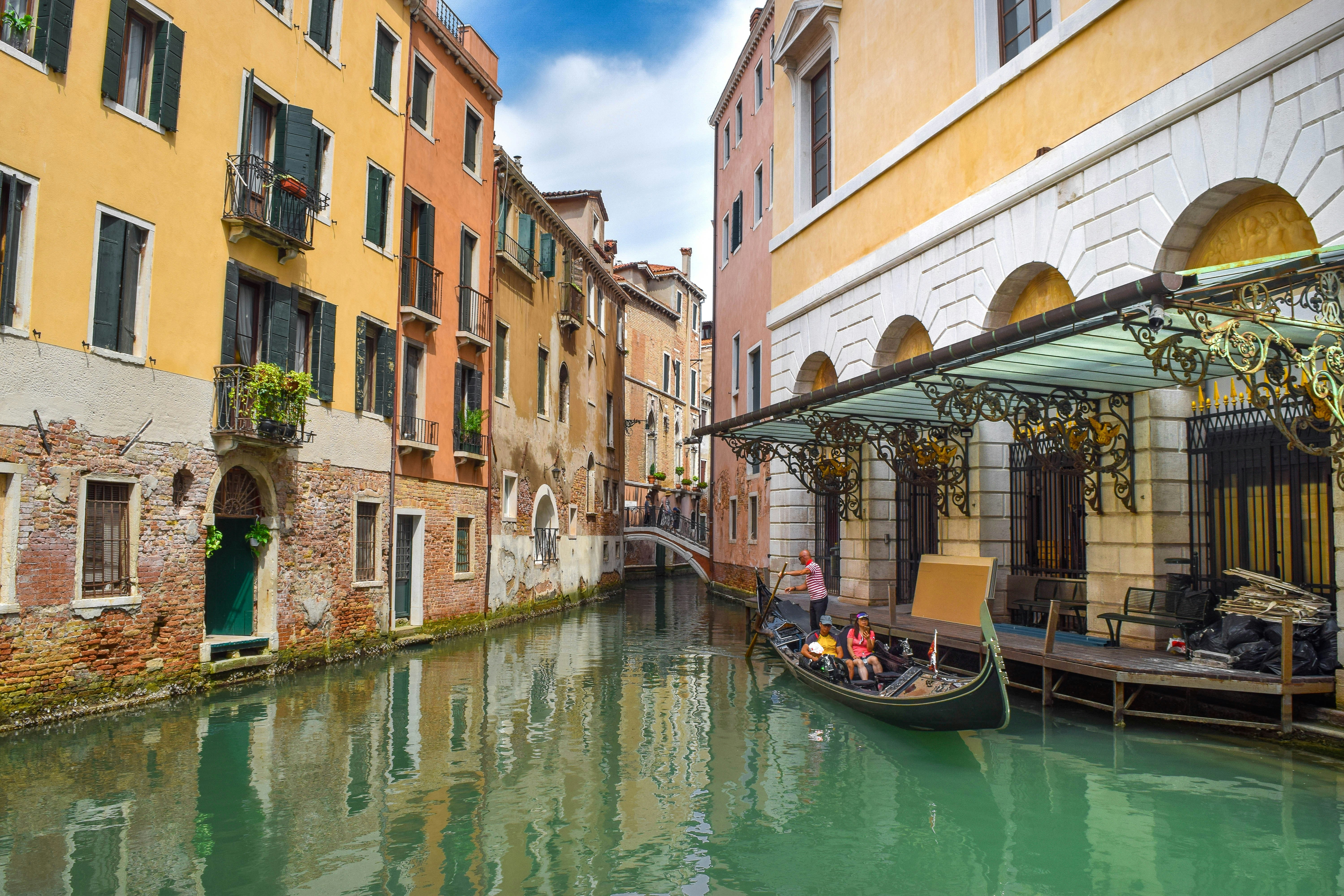 boat on river between buildings during daytime, Italy. Venetian streets.