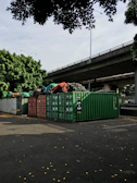 green trash bins on sidewalk during daytime