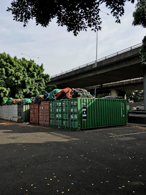 green trash bins on sidewalk during daytime