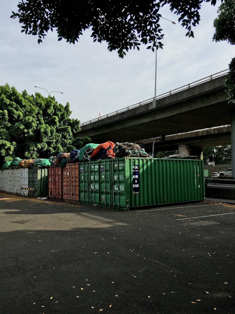 日中の歩道の緑のゴミ箱
