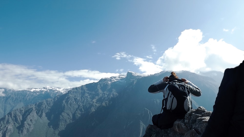 man in black jacket taking photo of snow covered mountain during daytime