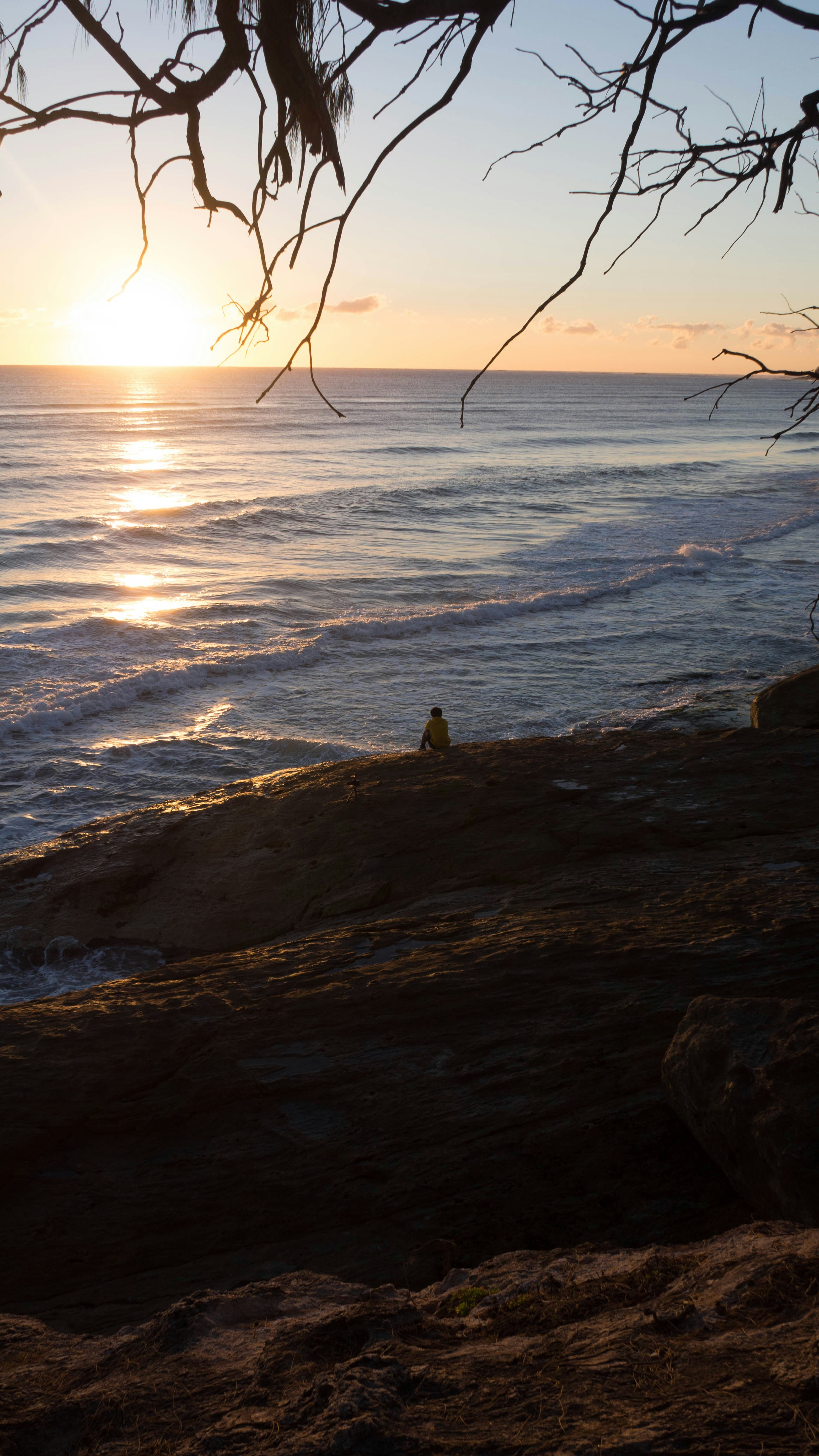 person sitting on rock near sea during daytime