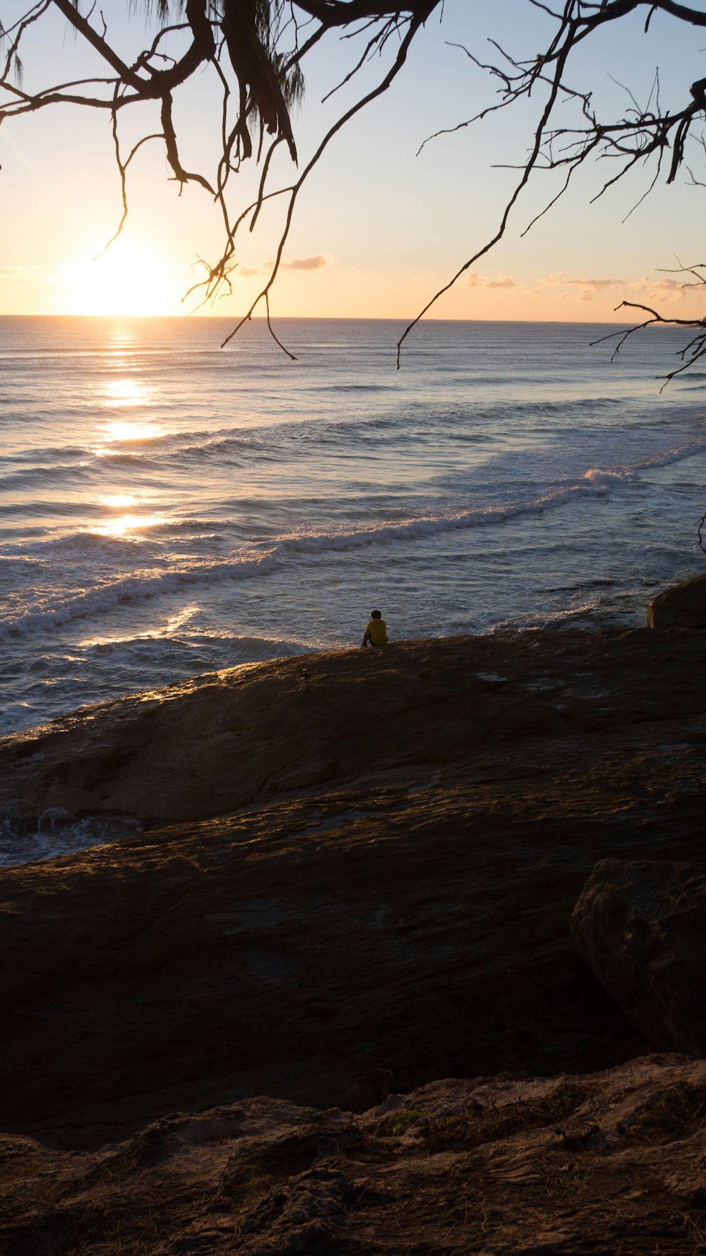 person sitting on rock near sea during daytime