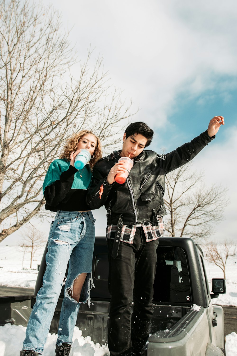 man in black leather jacket holding woman in blue denim jeans