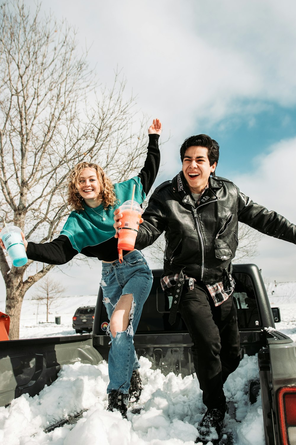 man in black leather jacket carrying girl in pink jacket