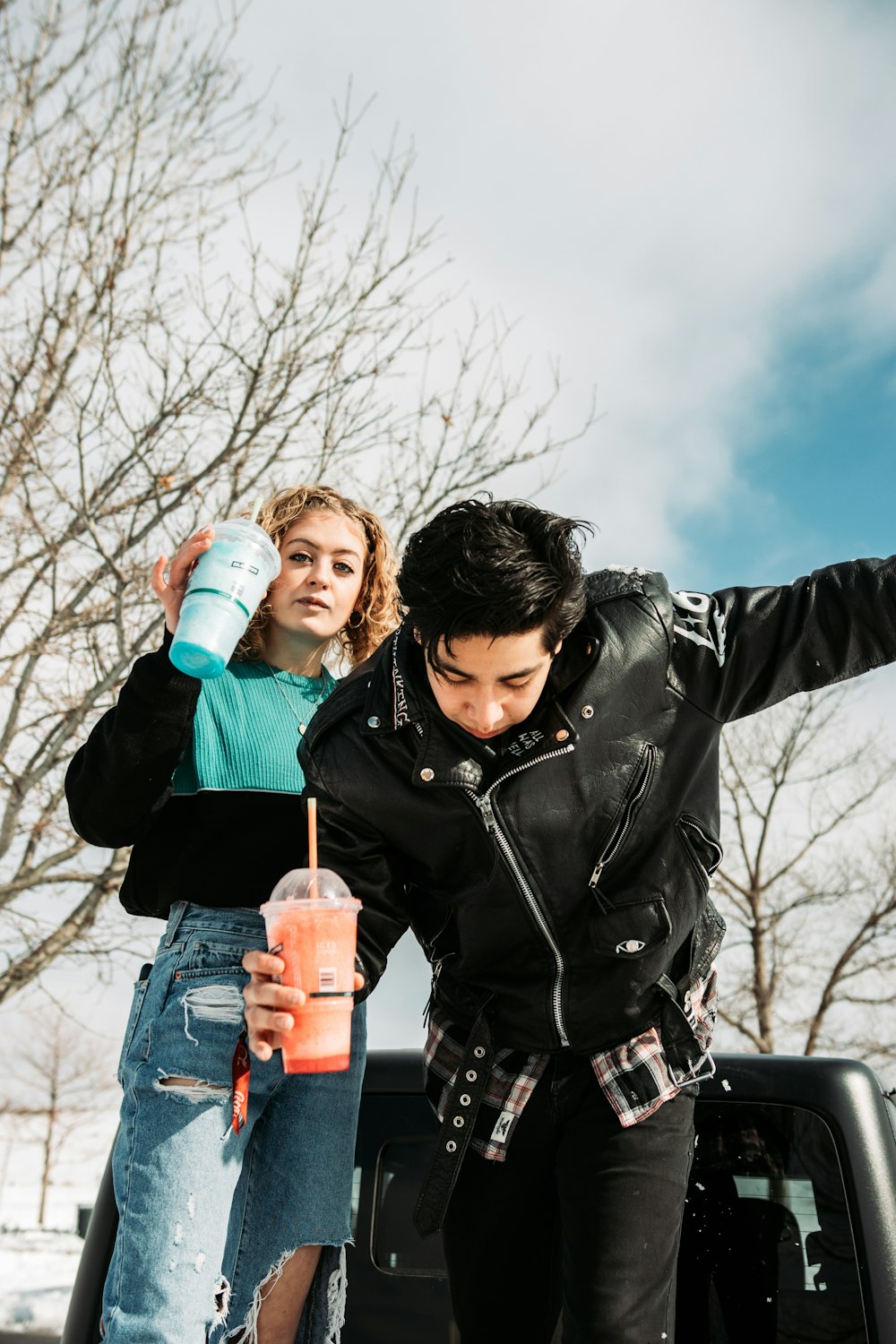 woman in black leather jacket holding white and blue plastic bottle