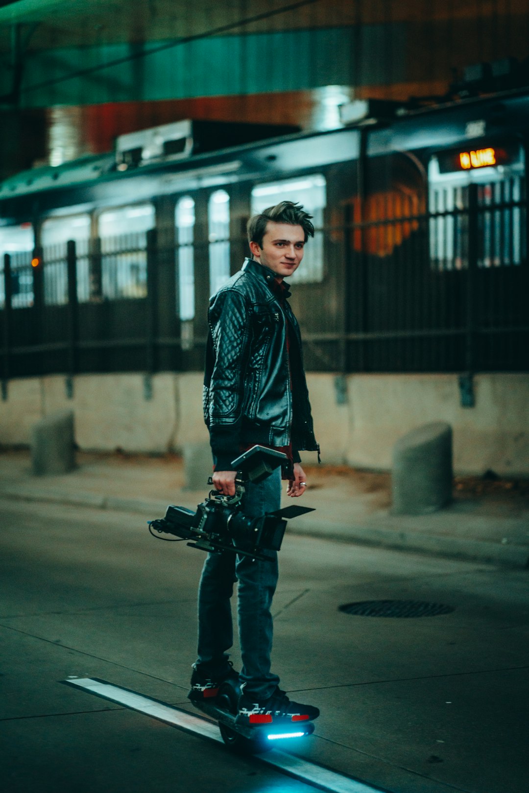 man in black jacket and black pants holding black dslr camera standing on sidewalk during daytime