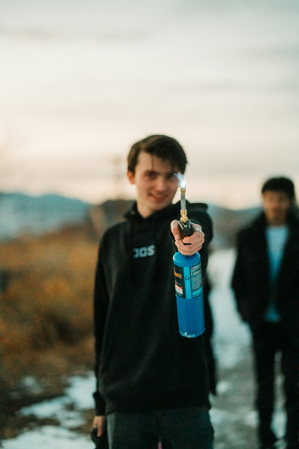 man in black sweater holding blue bottle