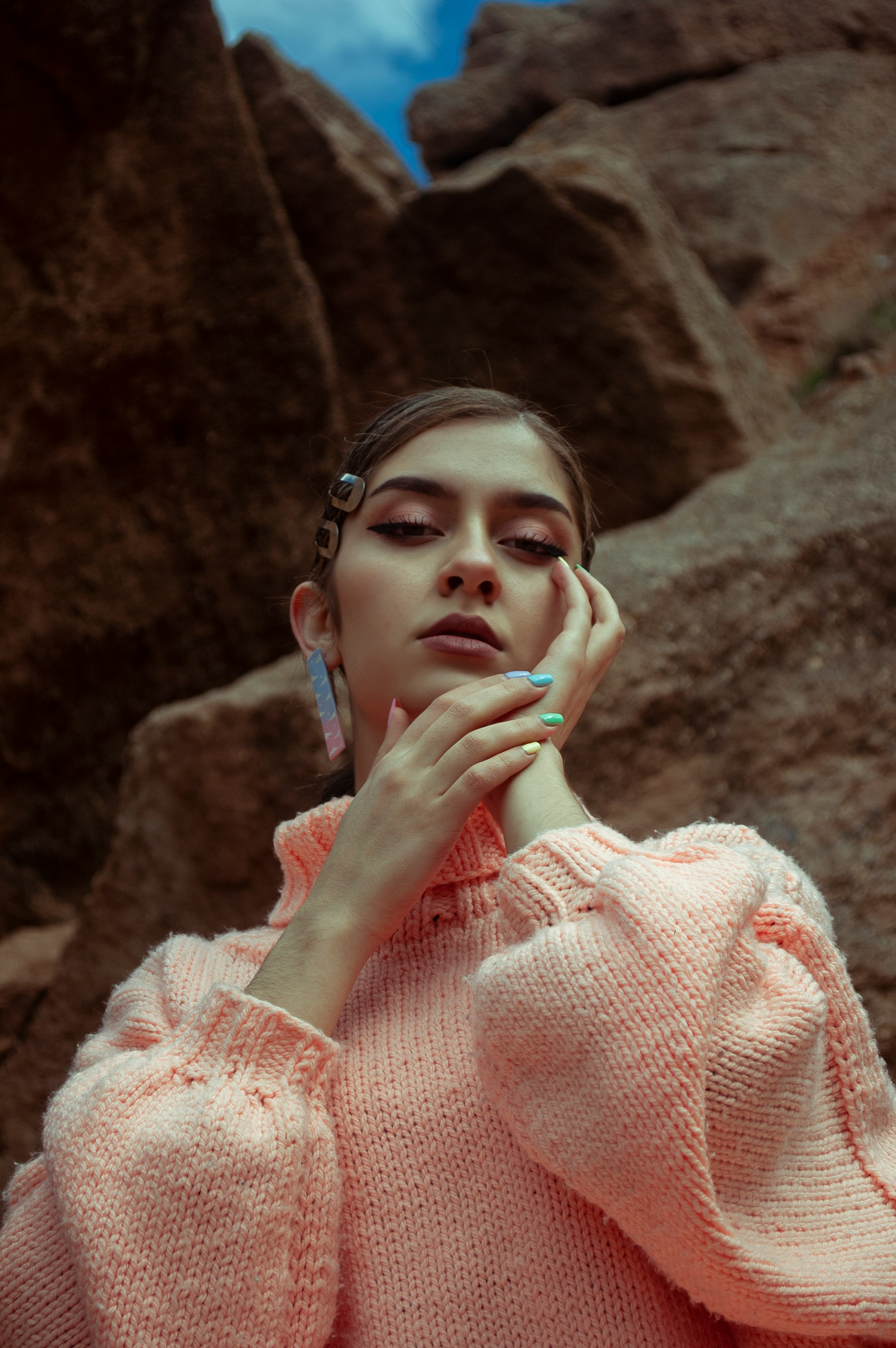 woman in pink sweater covering her face with her hand