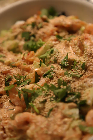 Close-up of a spoonful of tangy prawn pickle with fresh ingredients artfully arranged around it.