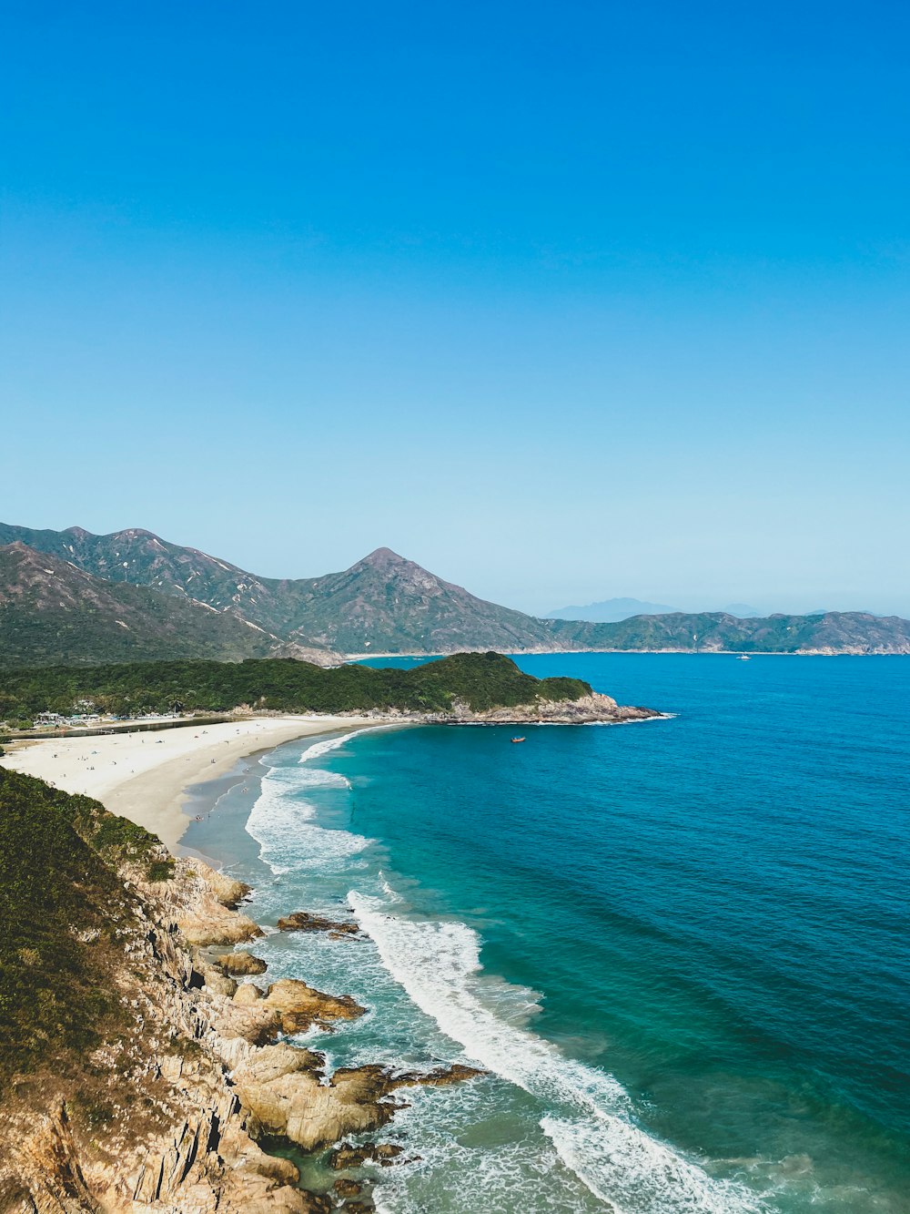 green mountain beside blue sea under blue sky during daytime