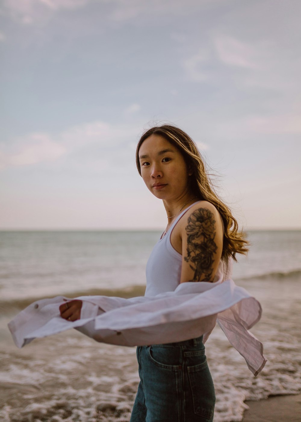 woman in white long sleeve shirt standing on beach during daytime