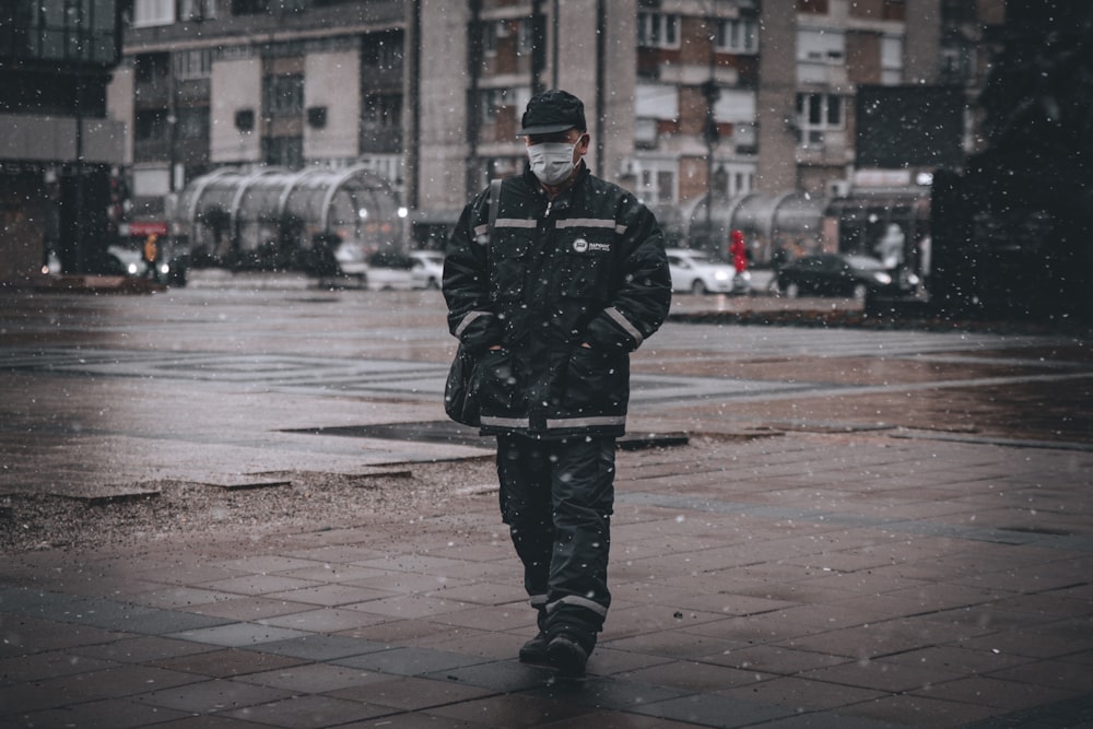 man in black coat standing on sidewalk during daytime