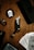 A tactical knife with intricate designs is placed on a wooden surface. Surrounding it are playing cards, a black ring, and black circular coasters featuring a white skull and crossbones symbol. The setup is complemented by a black box also adorned with the skull motif.