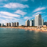 high rise buildings near sea under blue sky and white clouds during daytime