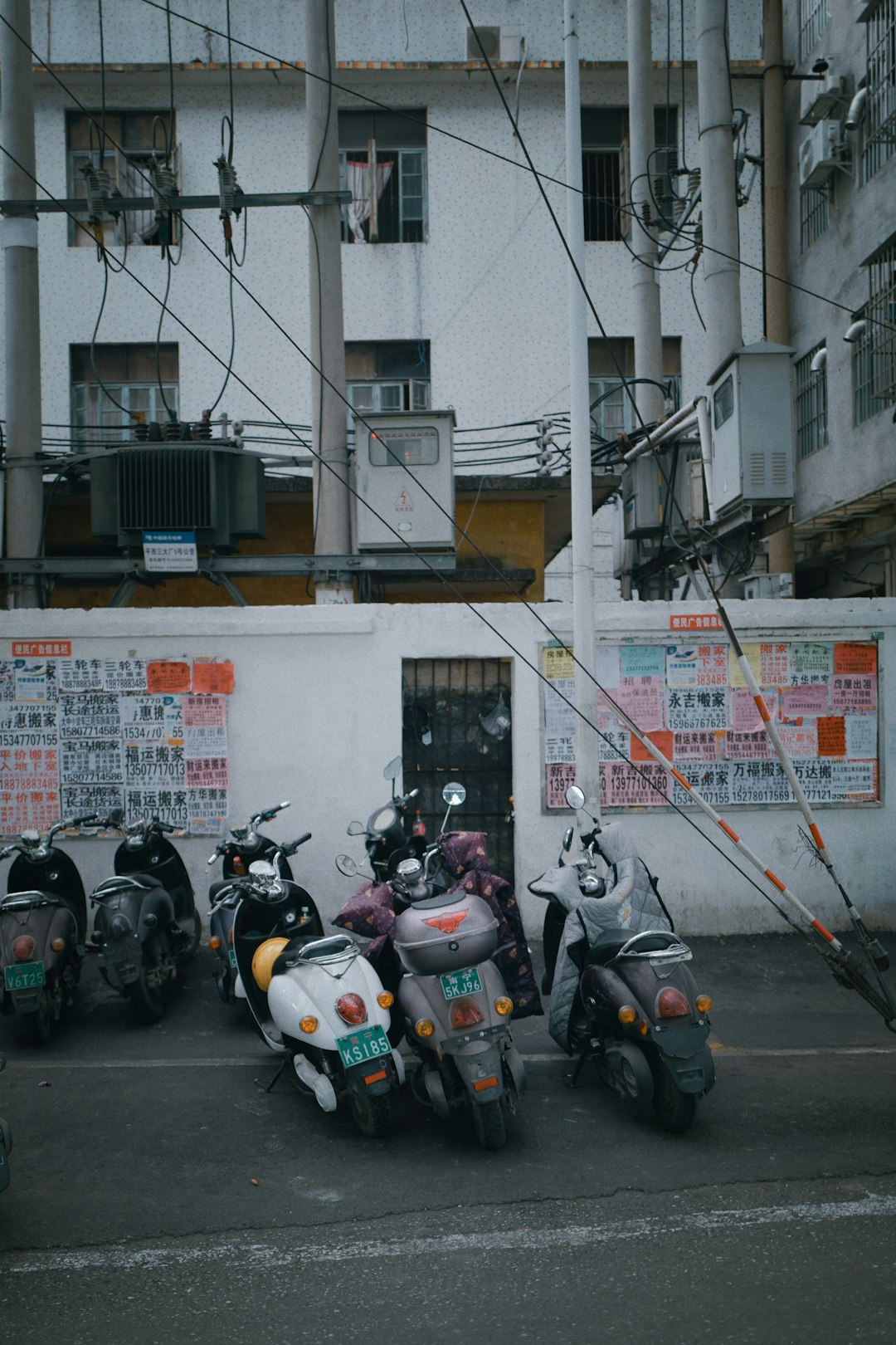 white and black motor scooter parked beside white wall