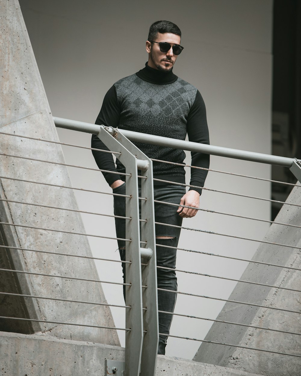 man in black long sleeve shirt and black sunglasses standing on stairs