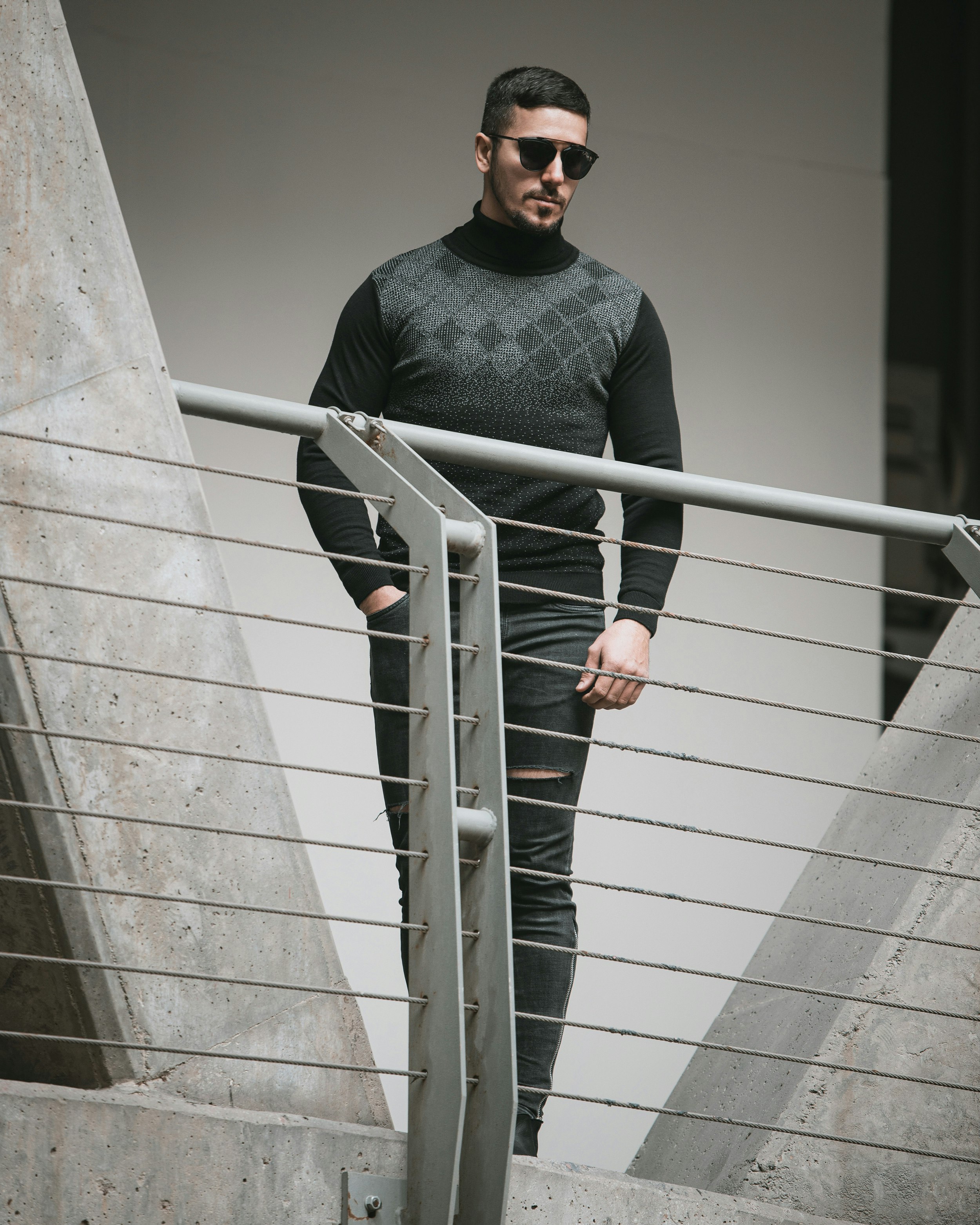 man in black long sleeve shirt and black sunglasses standing on stairs