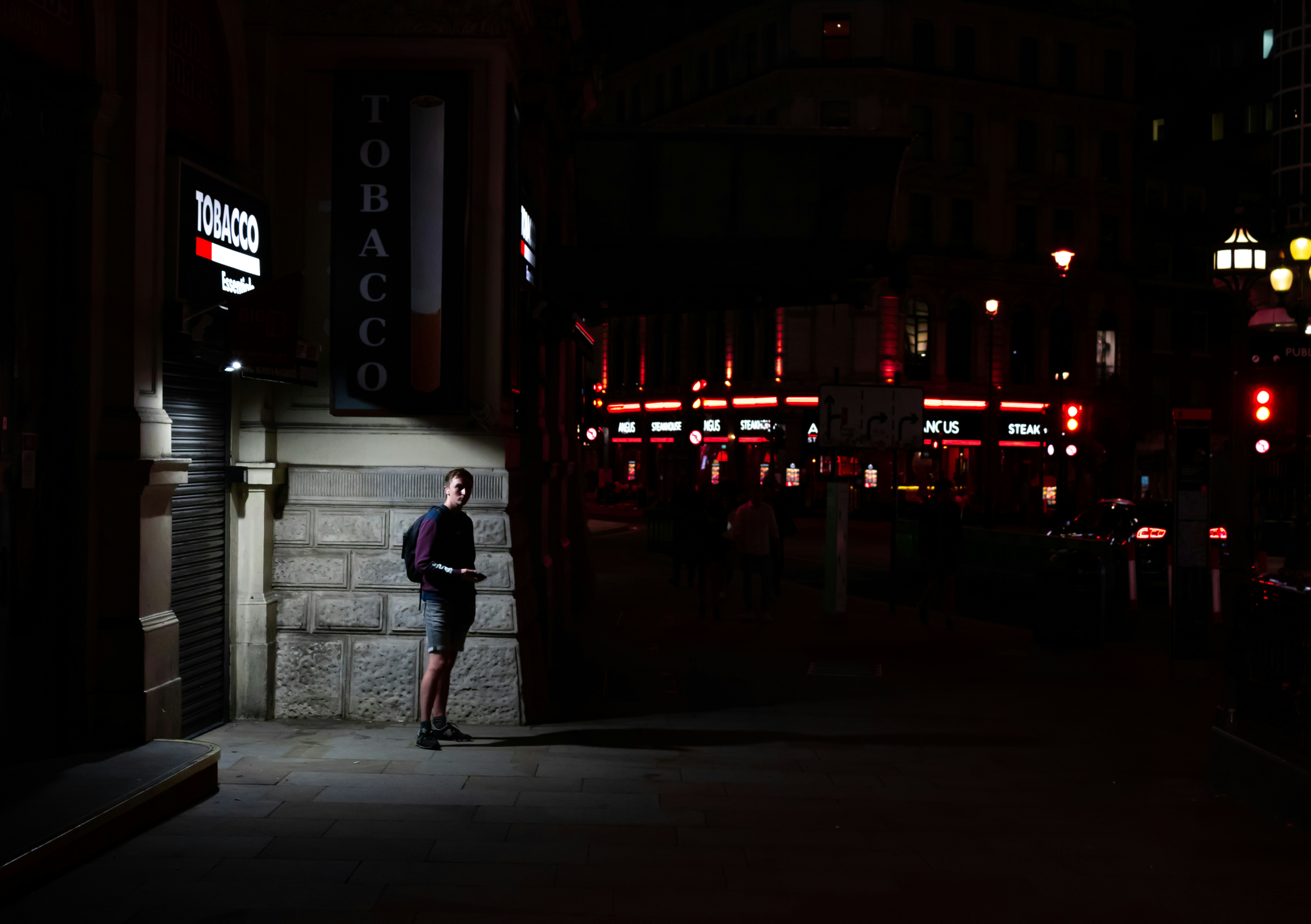 man in white shirt walking on sidewalk during night time