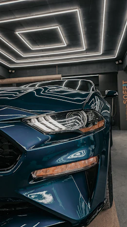 Side profile of a sophisticated luxury car with teal and copper tones shining under studio lights.