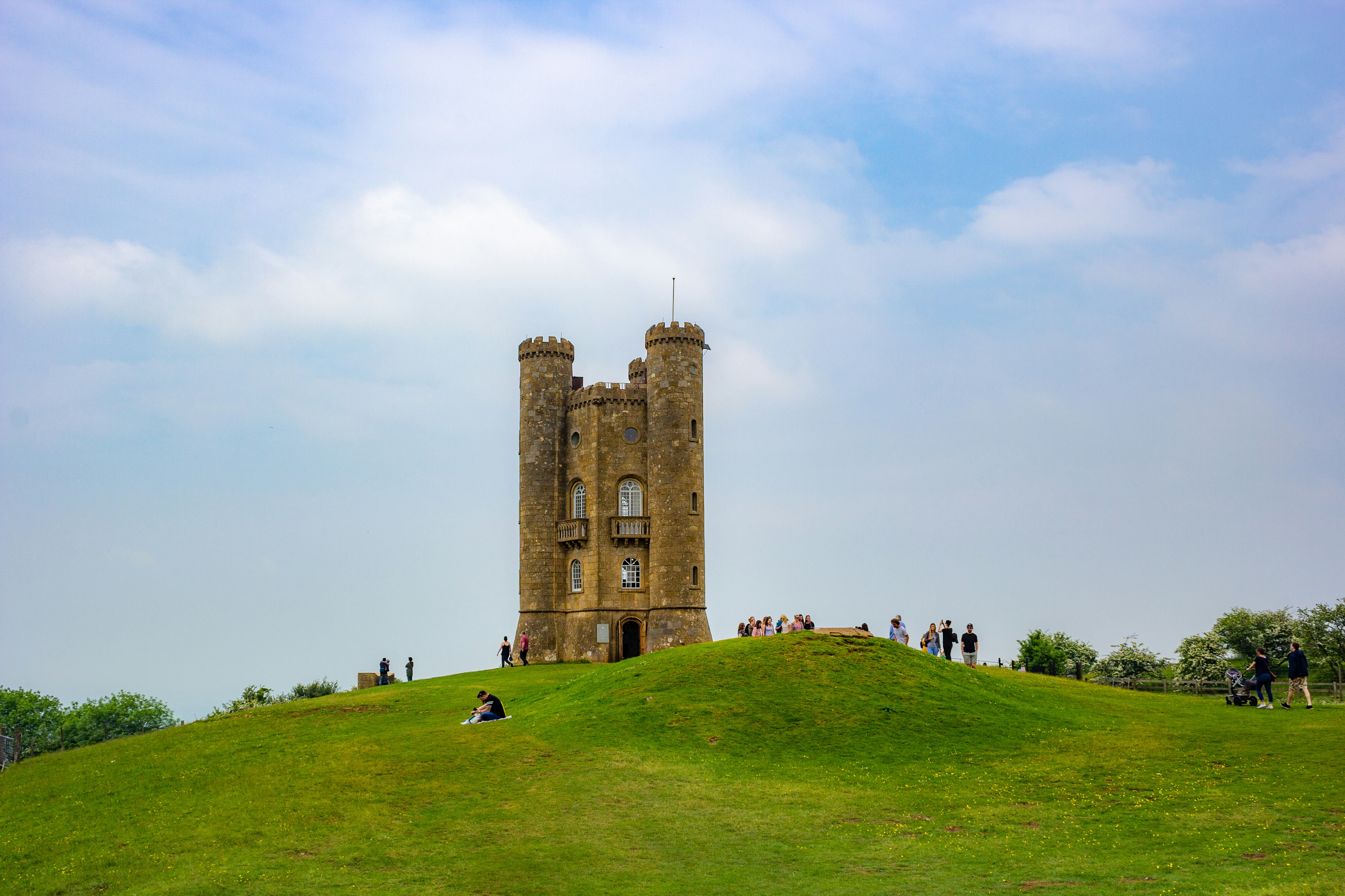 edificio in cemento marrone sul campo di erba verde sotto nuvole bianche durante il giorno