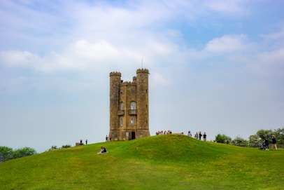 brown concrete building on green grass field under white clouds during daytime