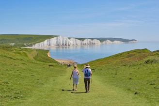 2 men standing on green grass field near body of water during daytime