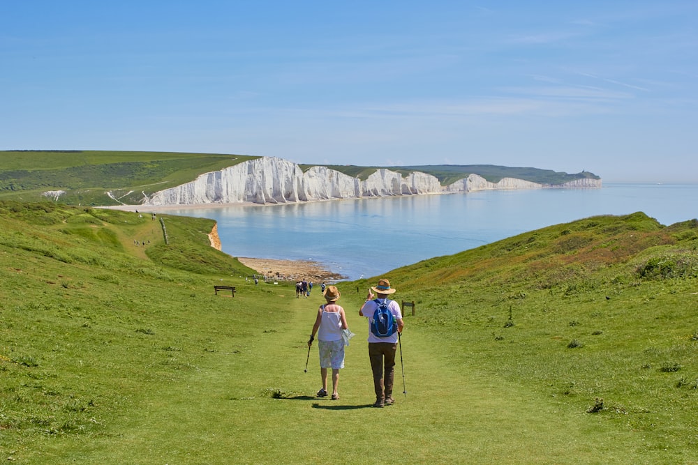 2 men standing on green grass field near body of water during daytime