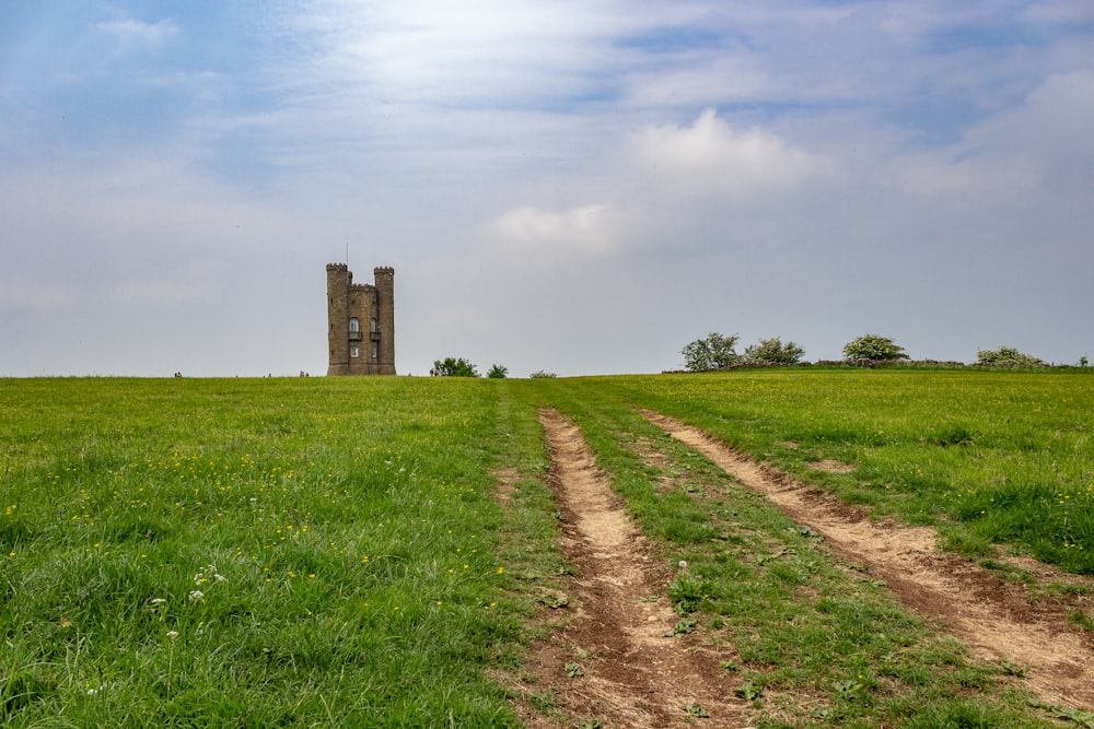 brown brick building on green grass field under white clouds during daytime