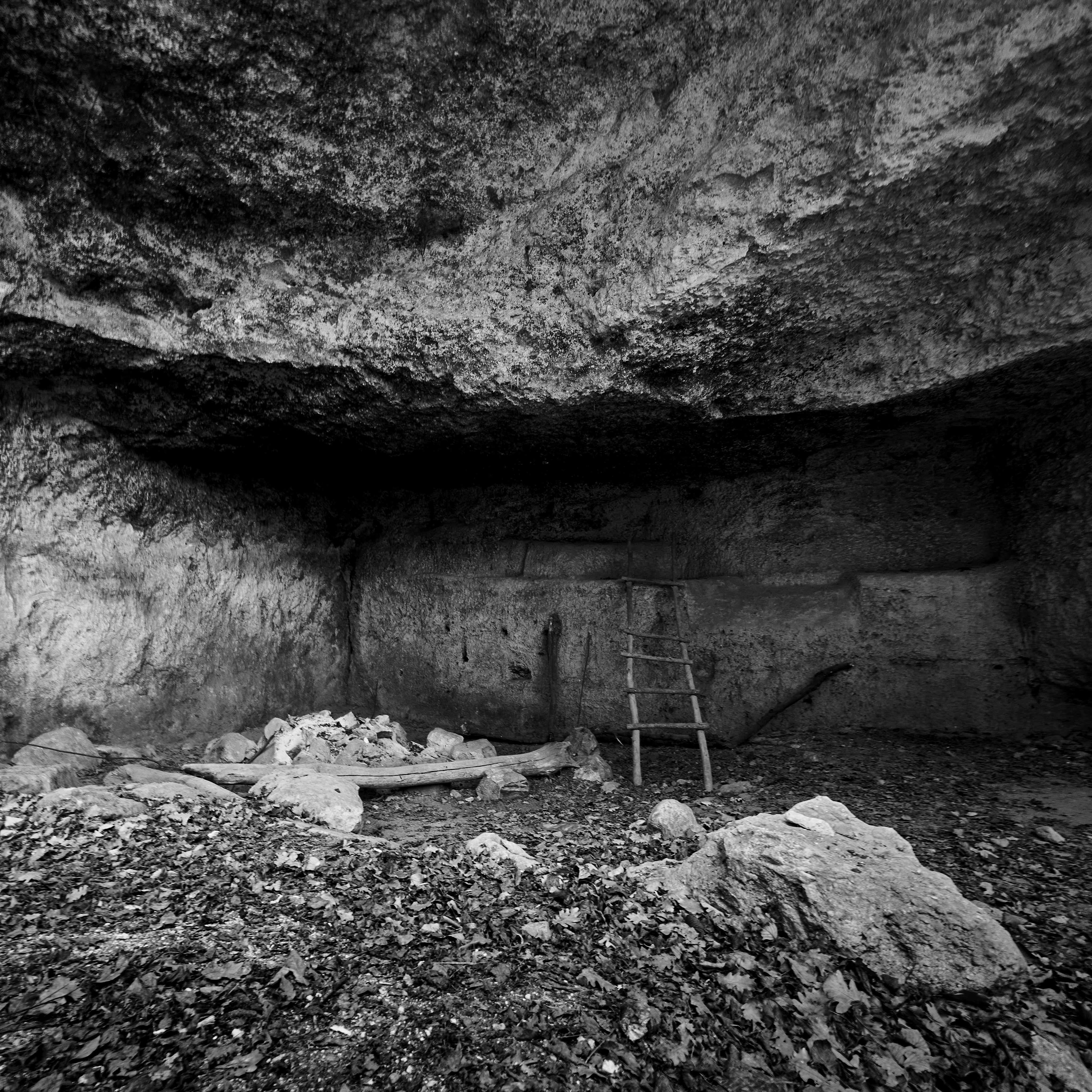 grayscale photo of person in cave