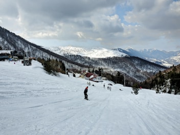Snowy mountain landscape with skiers descending a slope near the chalet.