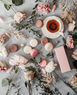 A soft pastel green and pink flat lay featuring matcha tea, skincare products, and delicate flowers