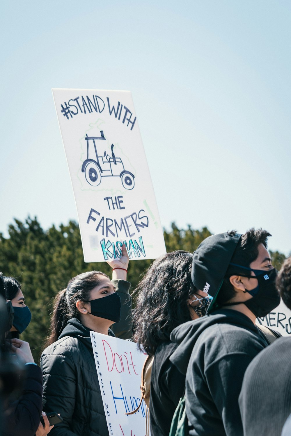 people standing and holding white and black banner during daytime