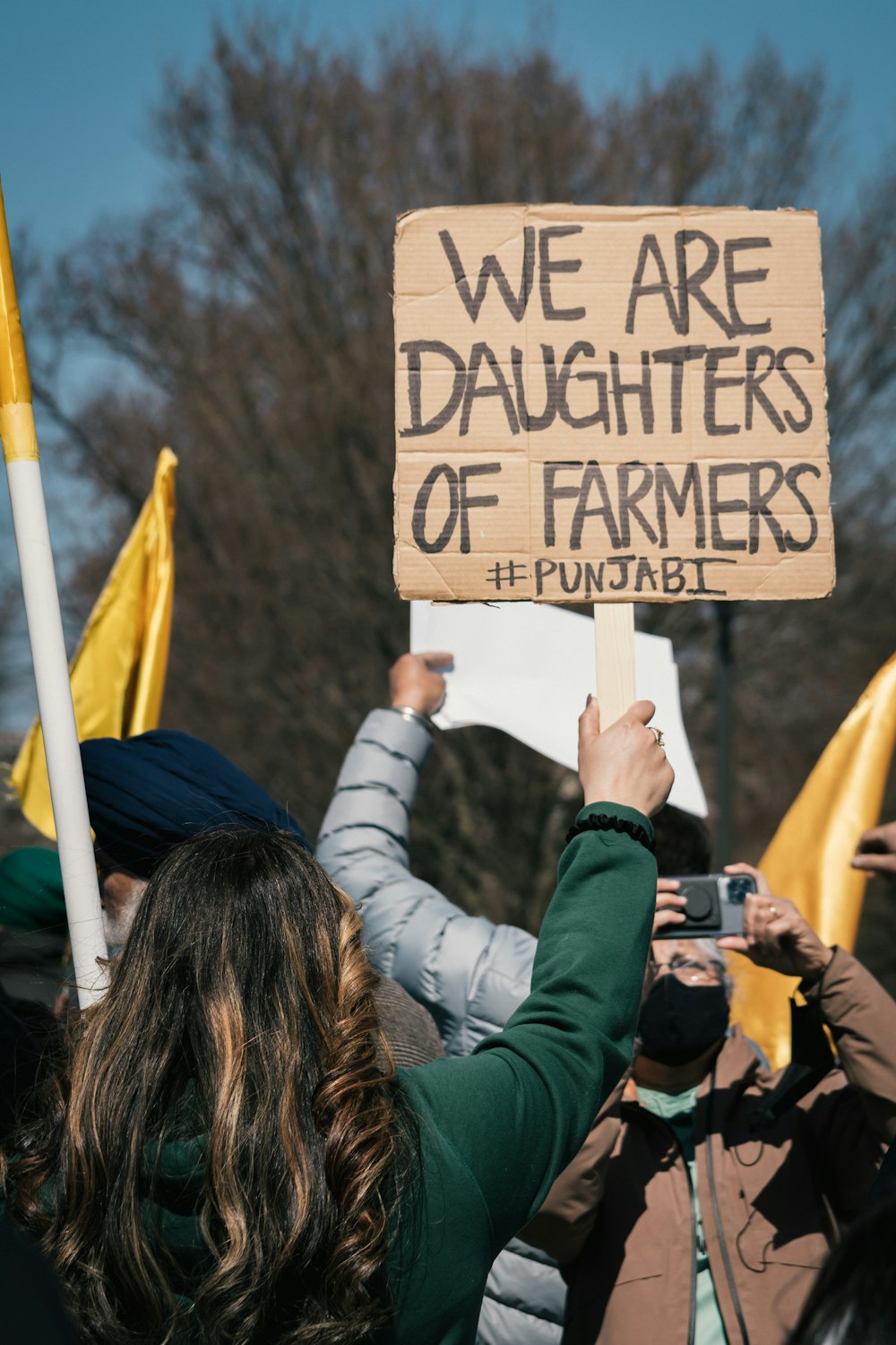 woman in green jacket holding brown wooden signage