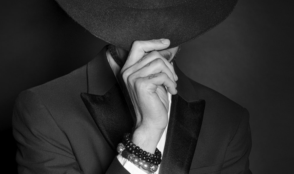 grayscale photo of man in black suit jacket wearing black and white beaded bracelet