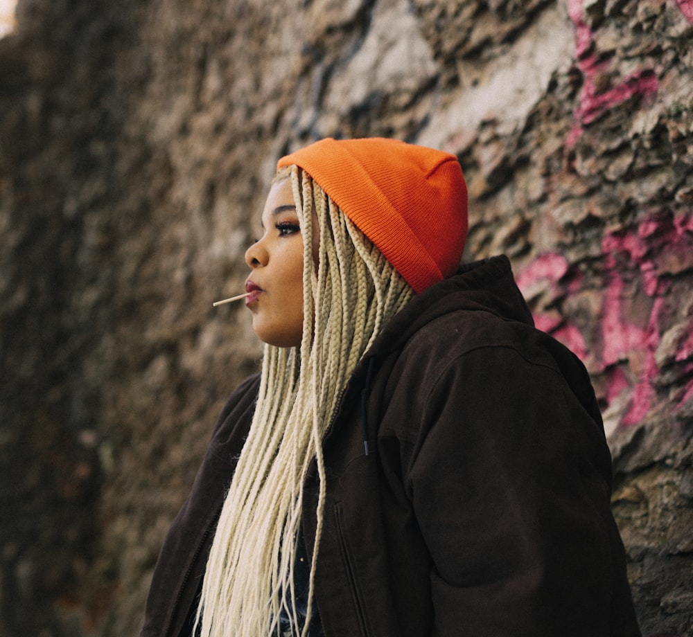 woman in black jacket wearing orange knit cap