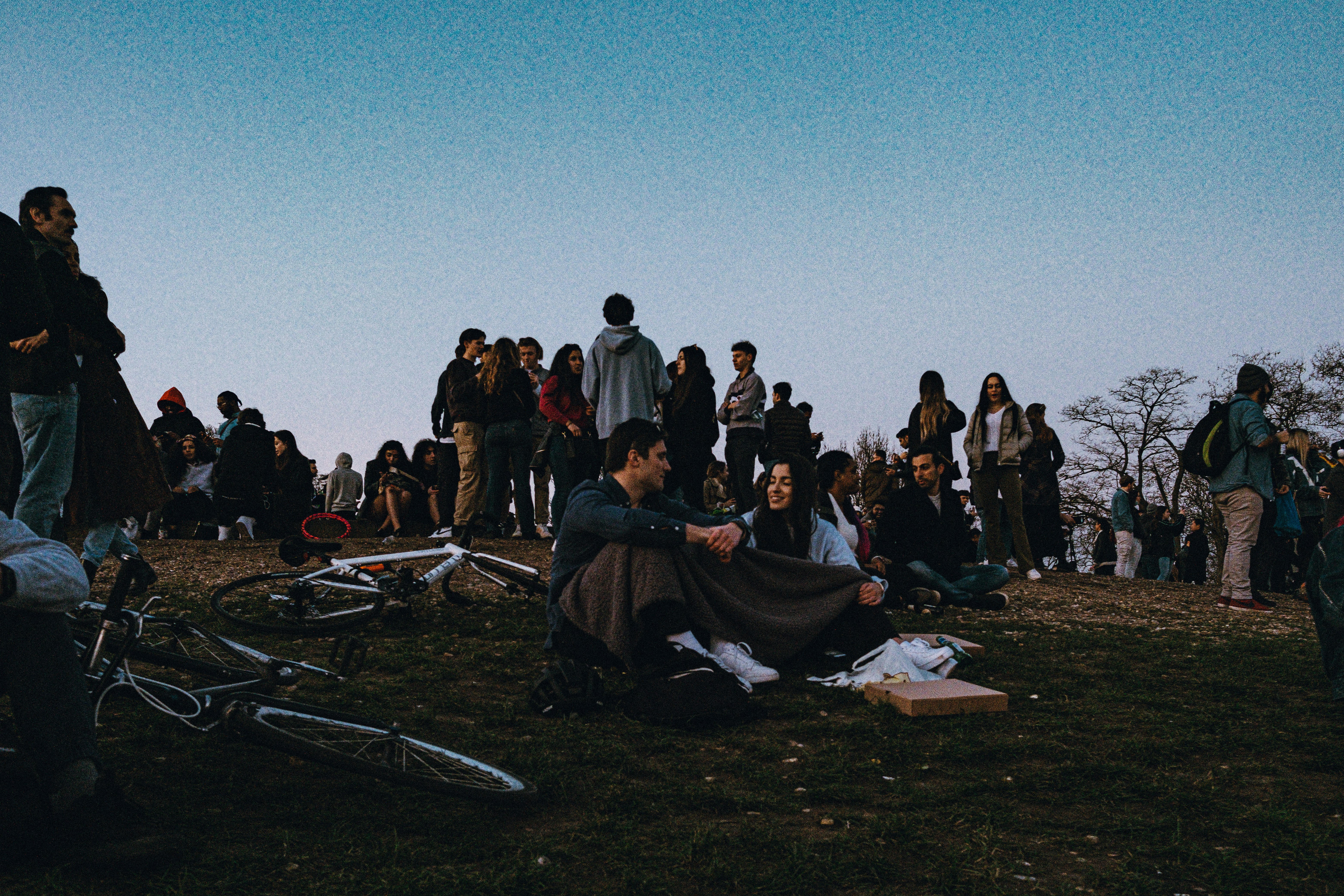 Community members at an outdoor awareness gathering, diverse group of young people, open sky background, engaged and attentive