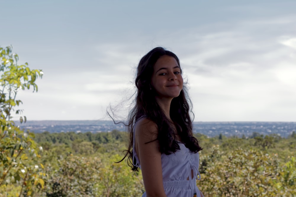 woman in white tank top standing on yellow flower field during daytime