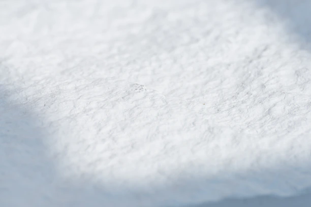 Close-up of a hand wiping a surface with a soft, white disposable cotton towel.