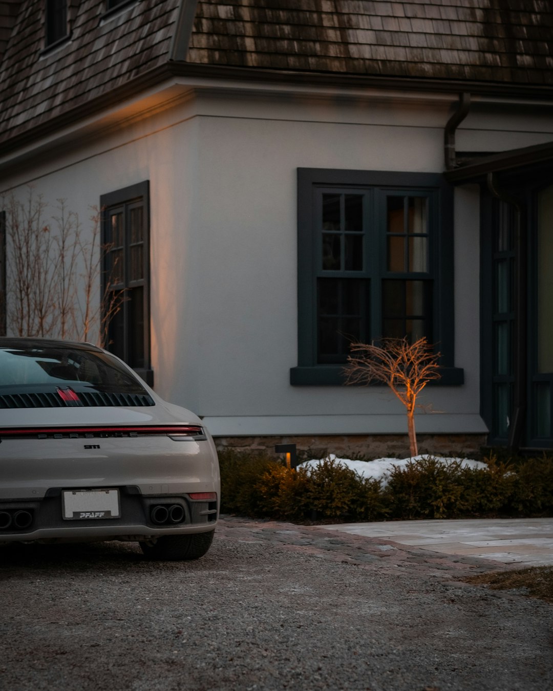 white bmw car parked beside gray house